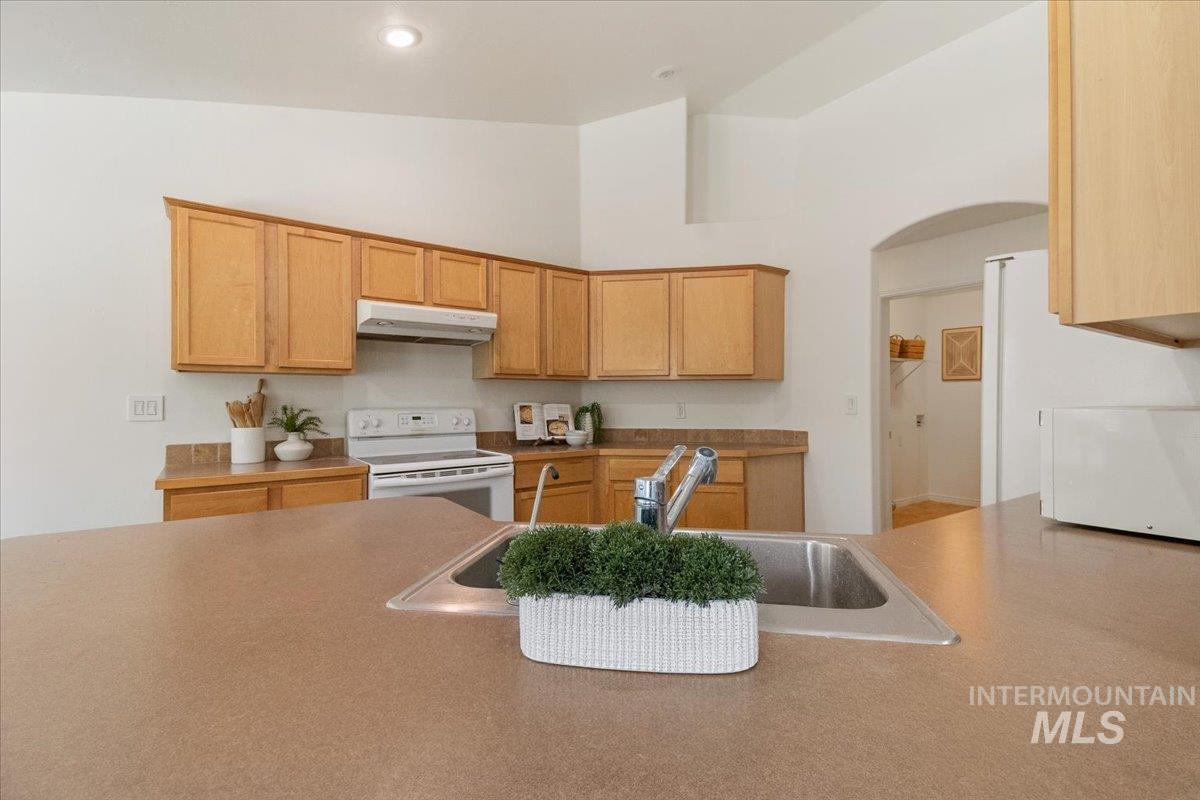 2032 Talus Loop Twin Falls, ID 83301 - Photo 17 of 43 Spacious kitchen featuring light wood cabinetry, a white range, and a dual-basin stainless steel sink