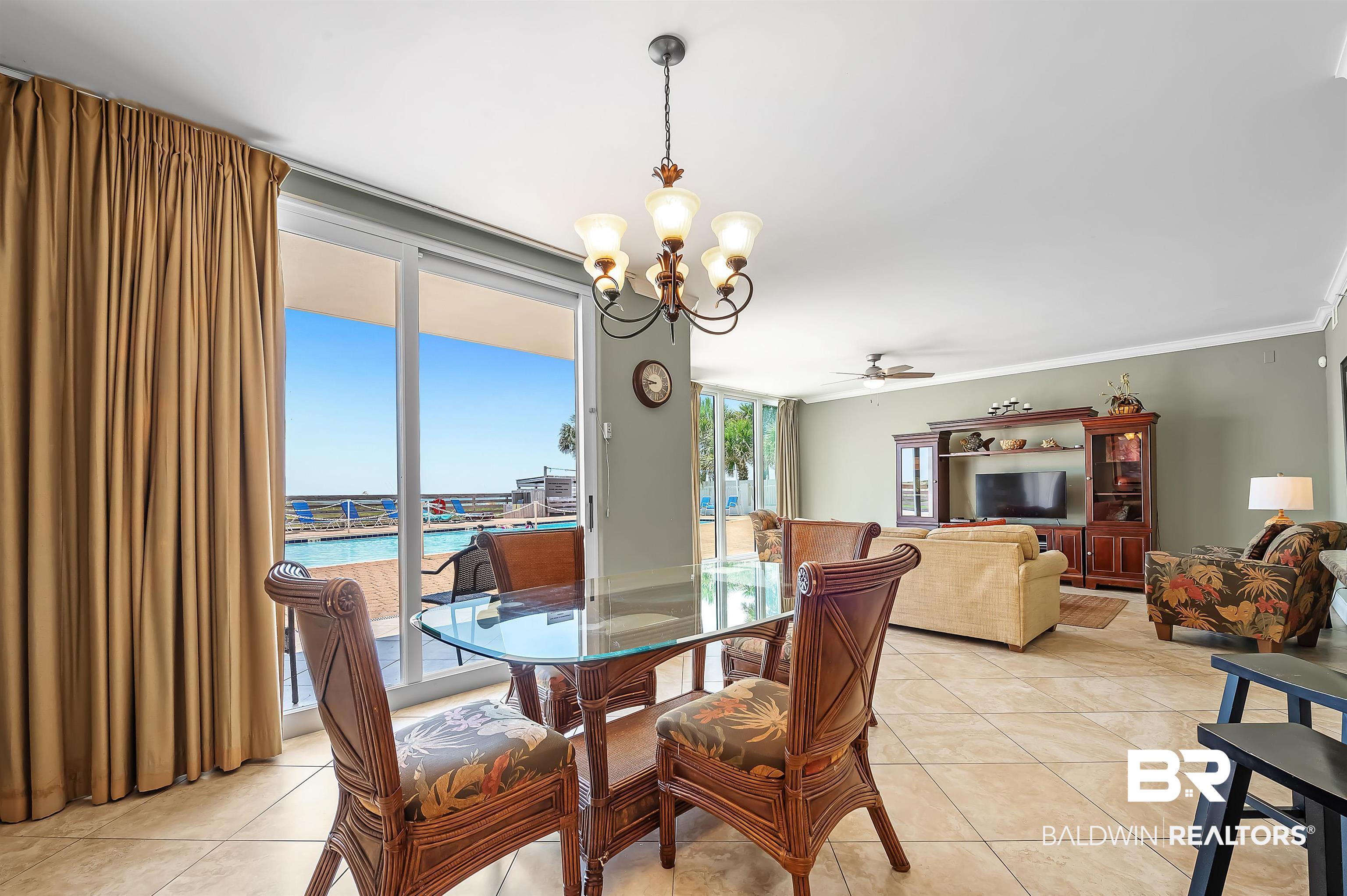 16287 Perdido Key Drive, Unit 105 Pensacola, FL 32507 - Photo 15 of 66 Open-concept living area featuring large format tile flooring, crown molding, and a chandelier lighting fixture