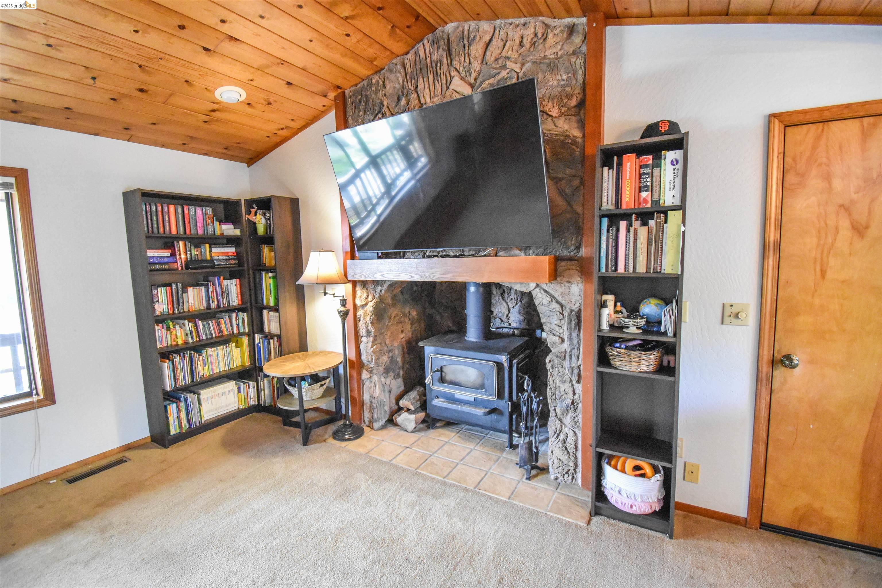 15 Roble Road Sonora, CA 95370 - Photo 13 of 44 Living area with a vaulted wood ceiling, light carpet, and a wood stove