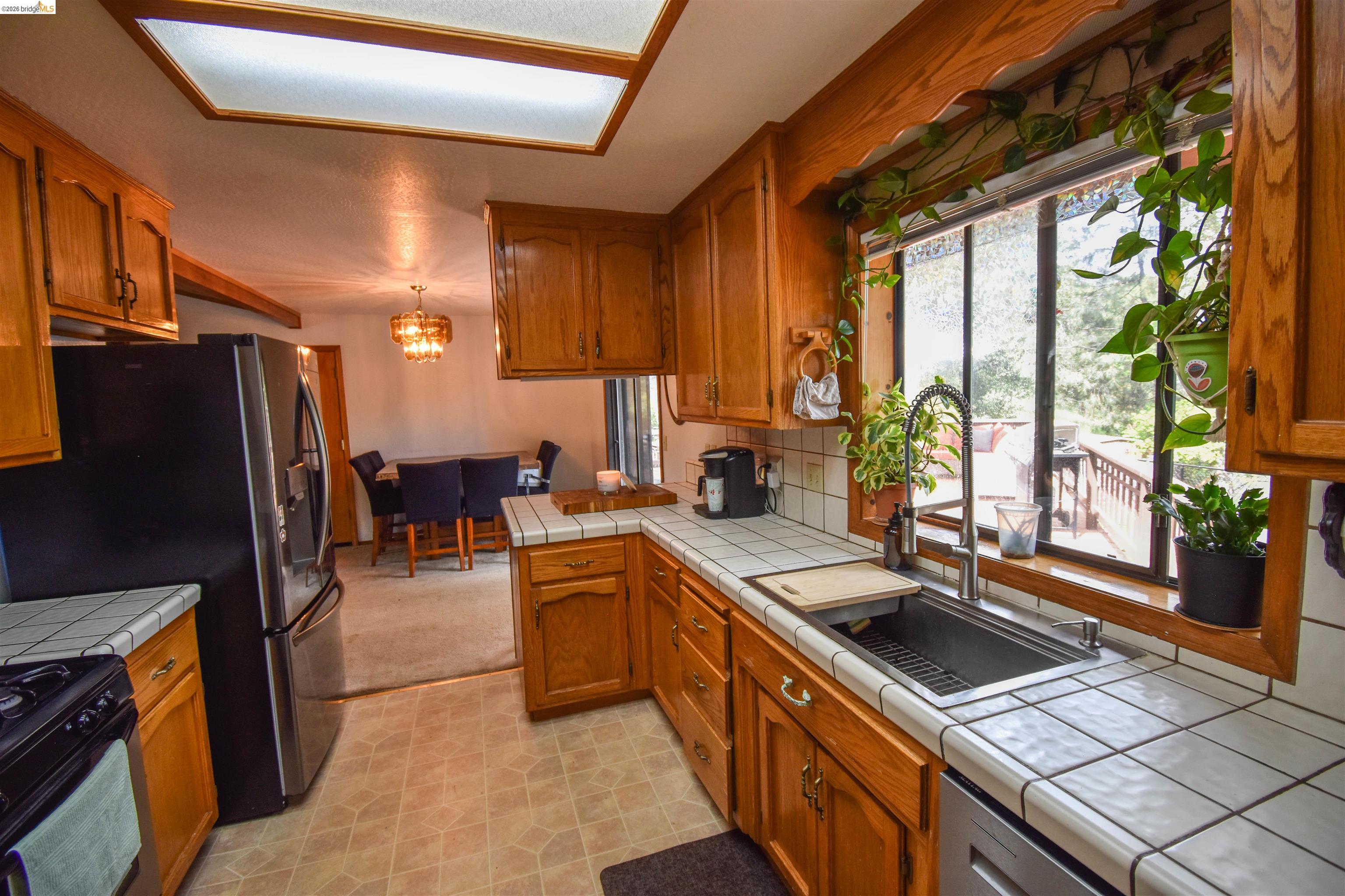 15 Roble Road Sonora, CA 95370 - Photo 17 of 44 Kitchen with wood finish cabinets, black gas range oven, tile countertops, backsplash, and hanging light fixtures