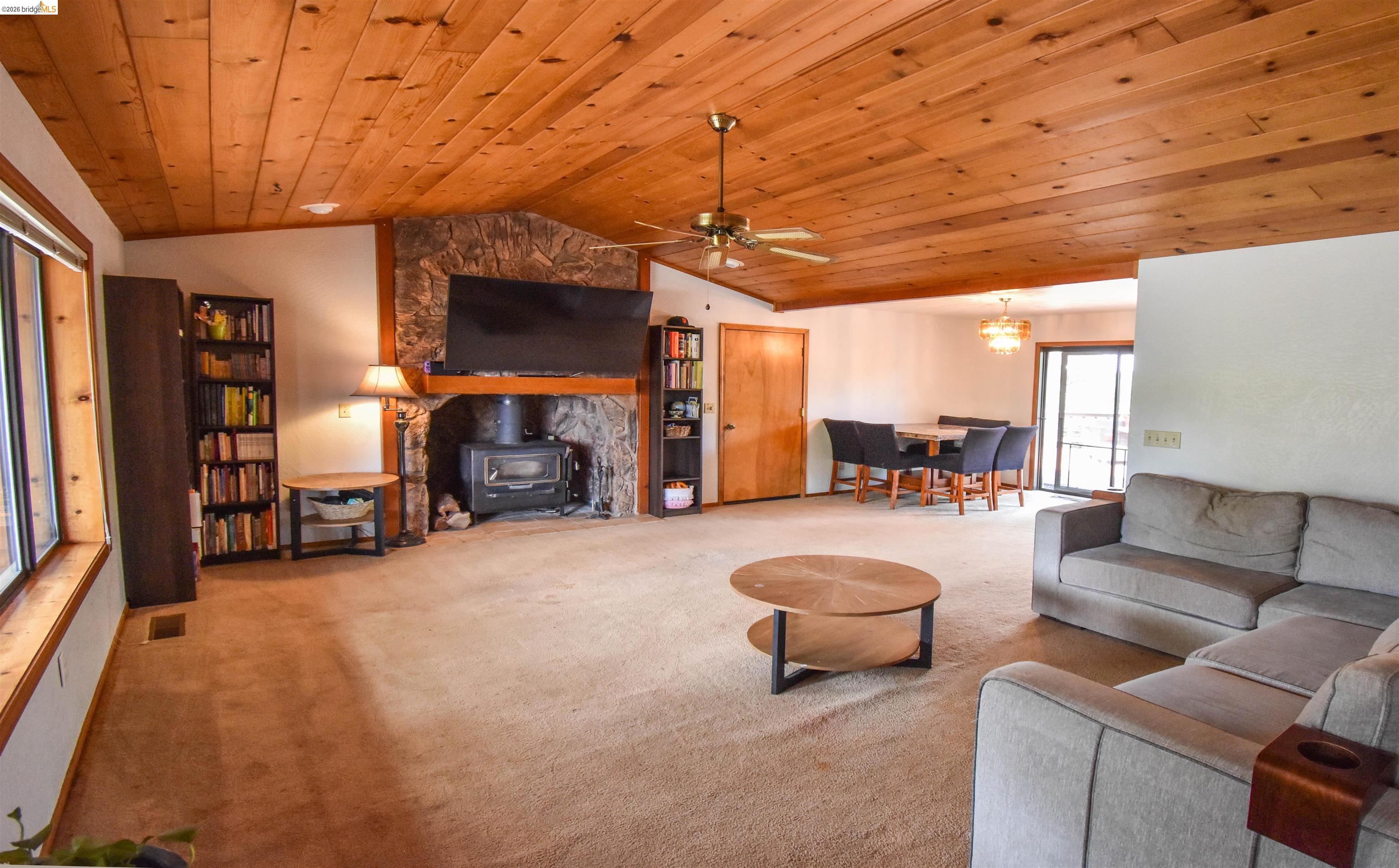 15 Roble Road Sonora, CA 95370 - Photo 8 of 44 Living area featuring a wood stove, ceiling fan, wooden ceiling, and carpet