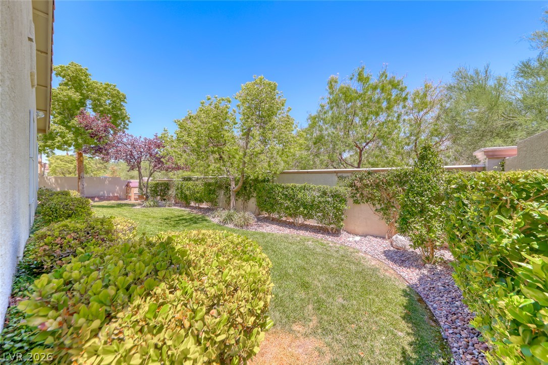 2122 Mooreview Street Henderson, NV 89012 - Photo 39 of 44 A verdant backyard retreat offers privacy and vibrant landscaping with mature trees.