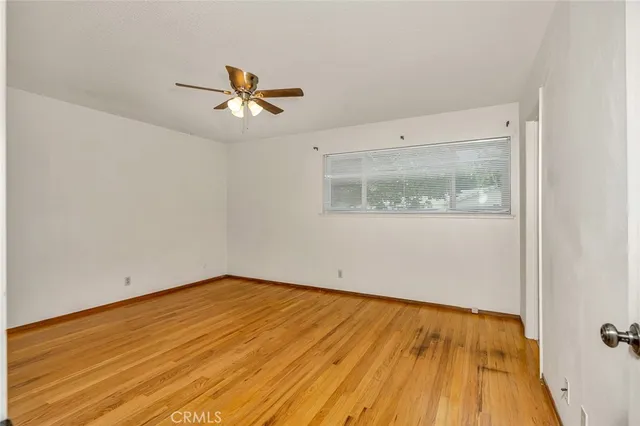 an empty room with wooden floor fan and windows
