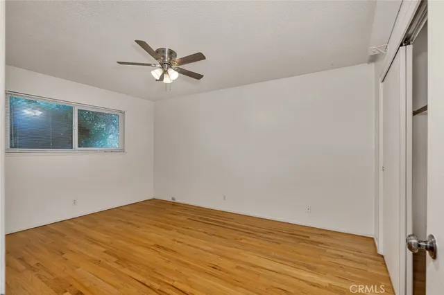 a view of a big room with wooden floor and a chandelier fan