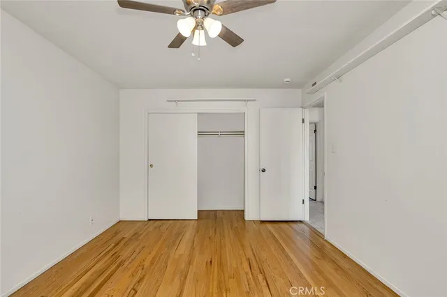 a view of empty room with wooden floor and fan