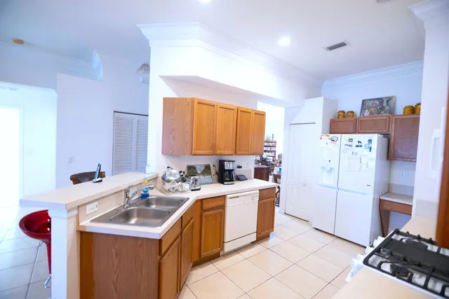 a view of a white house with a big yard and potted plants and large trees