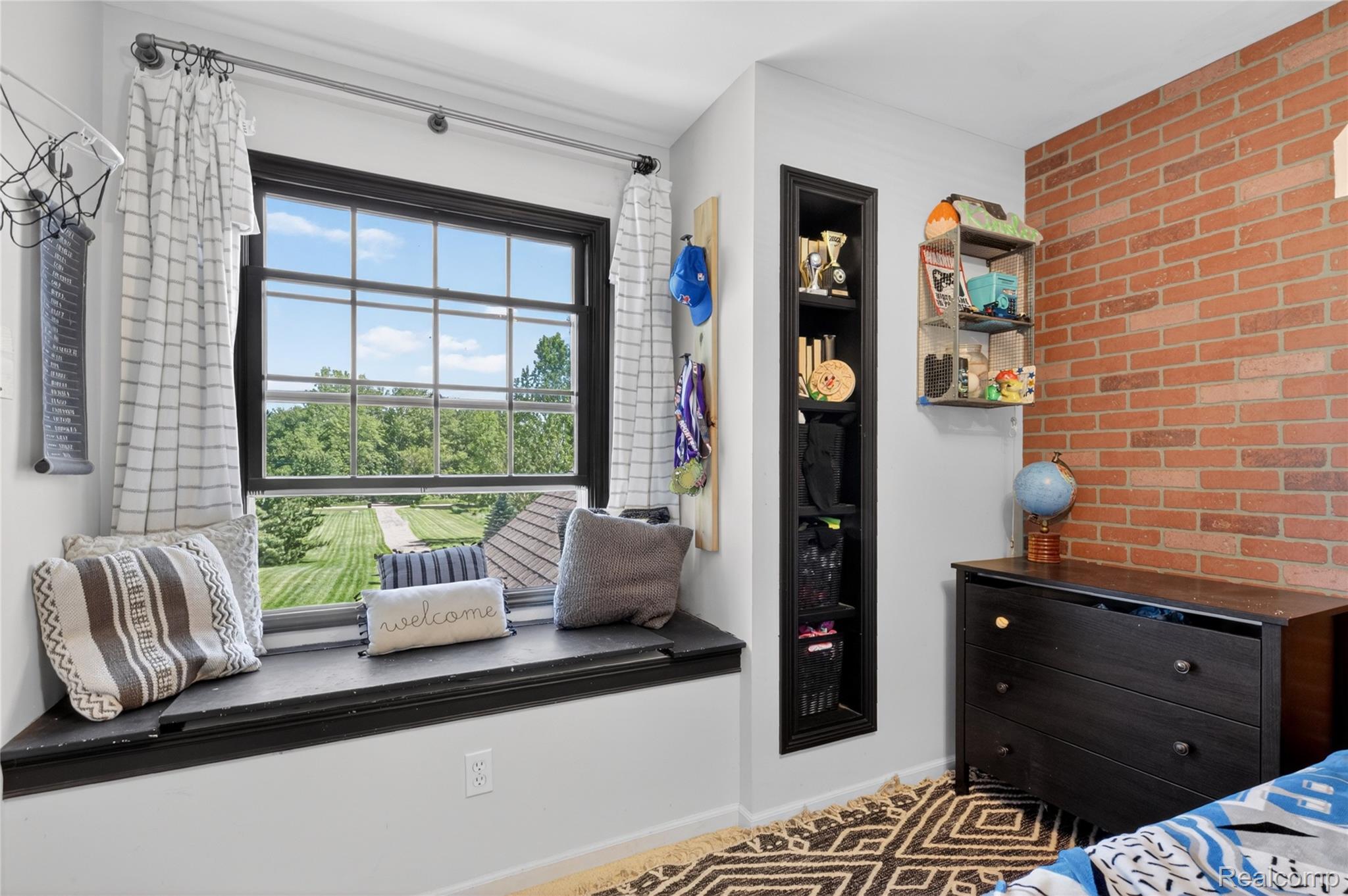 9191 Judd Road Fowlerville, MI 48836 - Photo 55 of 74 Window seat with black trim, built-in shelving, and a brick accent wall