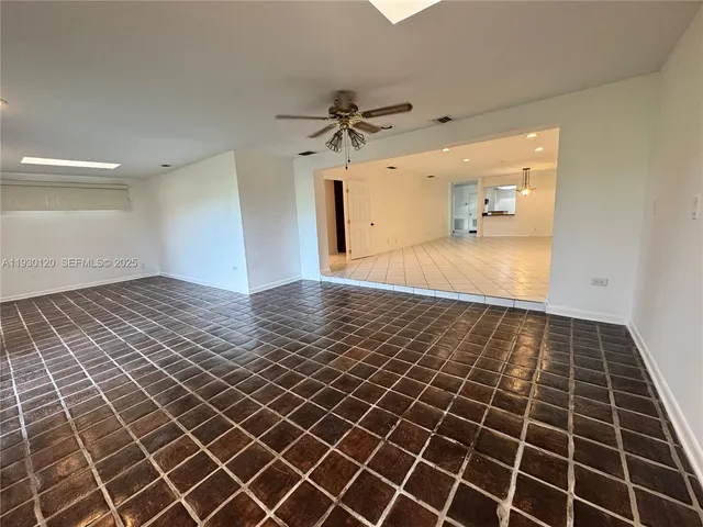 an empty room with wooden floor and a ceiling fan
