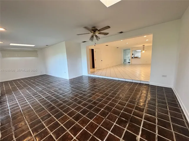 a view of an empty room and chandelier fan