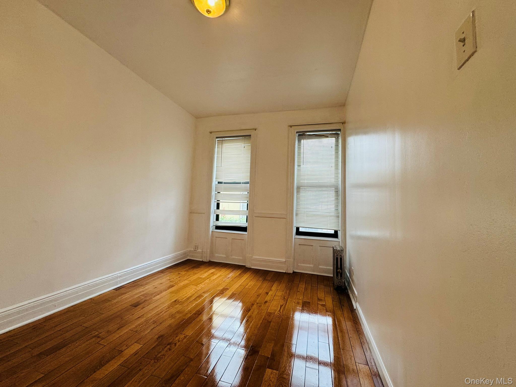 25-38 22nd Street, Unit 1 Queens, NY 11102 - Photo 5 of 19 an empty room with wooden floor and windows