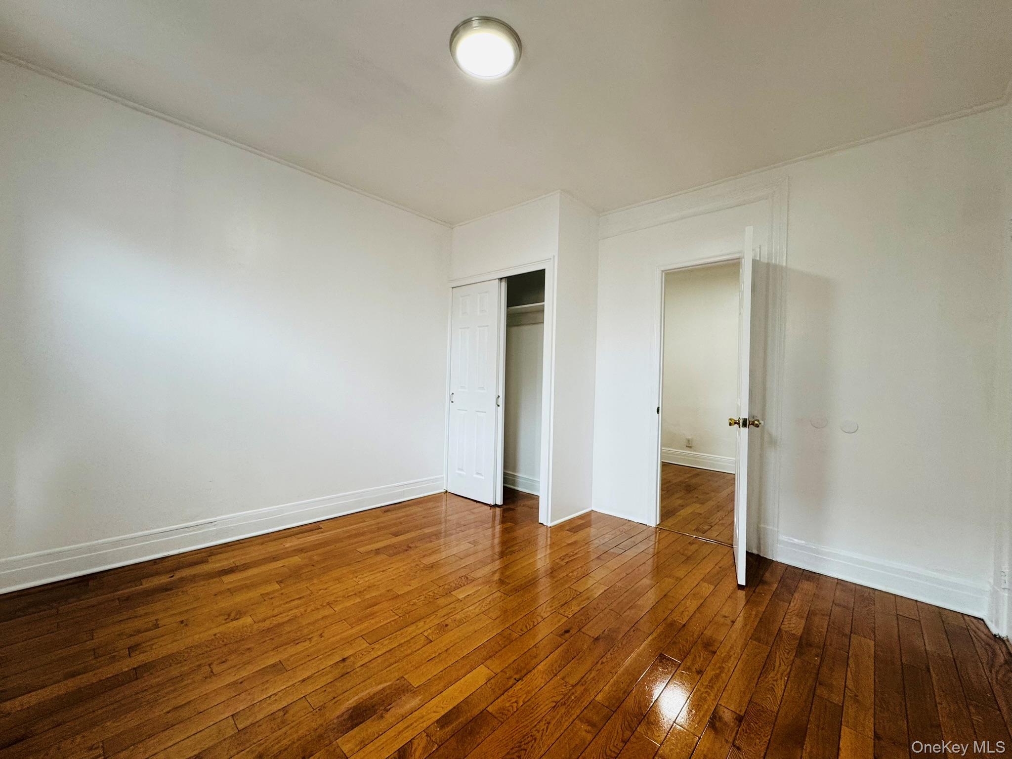 25-38 22nd Street, Unit 1 Queens, NY 11102 - Photo 9 of 19 an empty room with wooden floor and windows