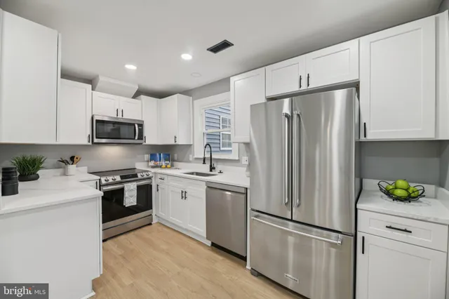 a kitchen with stainless steel appliances granite countertop a refrigerator stove a sink and dishwasher with white cabinets