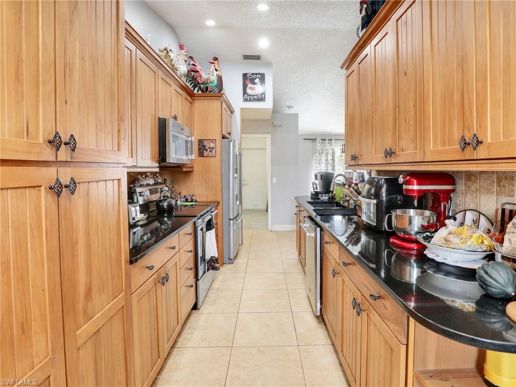 9083 Aster Road Fort Myers, FL 33967 - Photo 12 of 30 a kitchen with stainless steel appliances granite countertop a refrigerator and a stove
