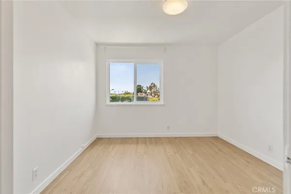 an empty room with wooden floor and a ceiling fan