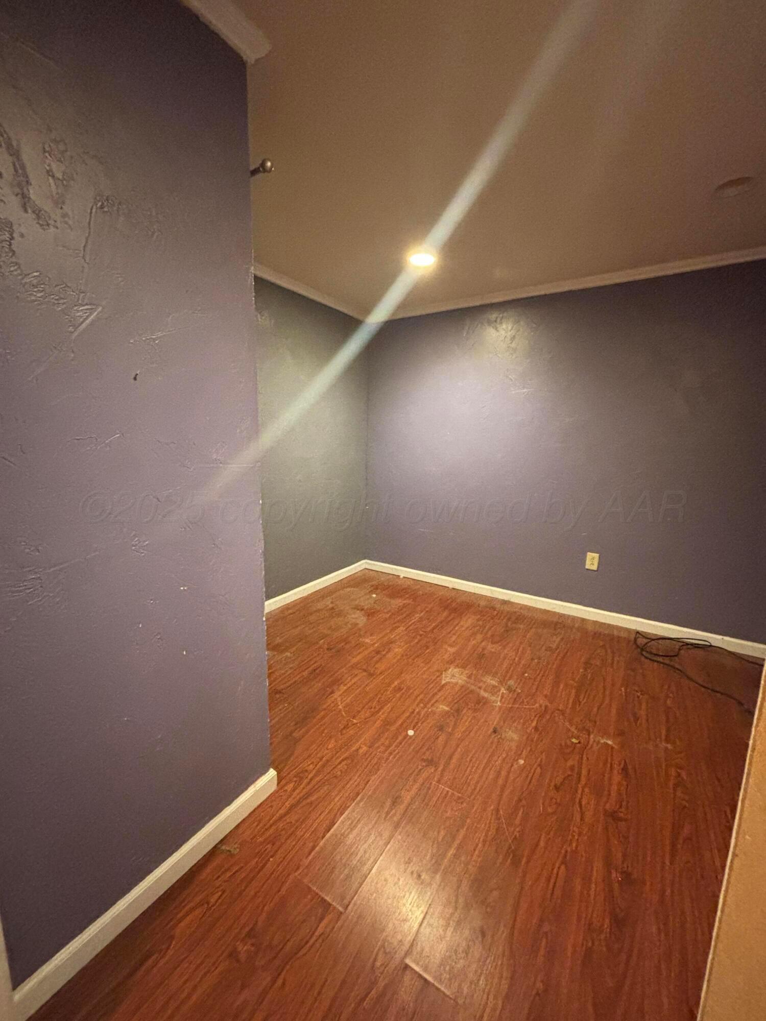 206 Harvey Street Miami, TX 79059 - Photo 7 of 7 an empty room with wooden floor and windows