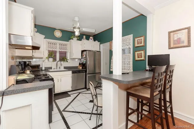 a kitchen with stainless steel appliances kitchen island granite countertop a table chairs and a refrigerator