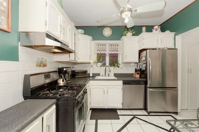 a kitchen with stainless steel appliances granite countertop a sink a stove a refrigerator and cabinets