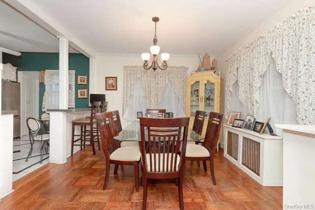 a dining room with wooden floor a chandelier a wooden table and chairs