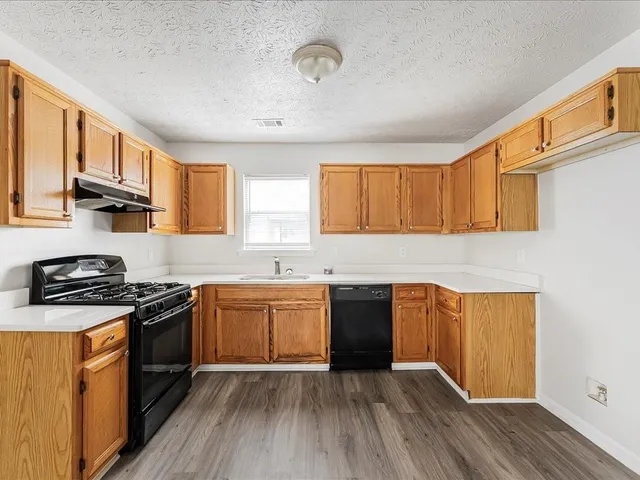 a kitchen with granite countertop a stove top oven sink and cabinets