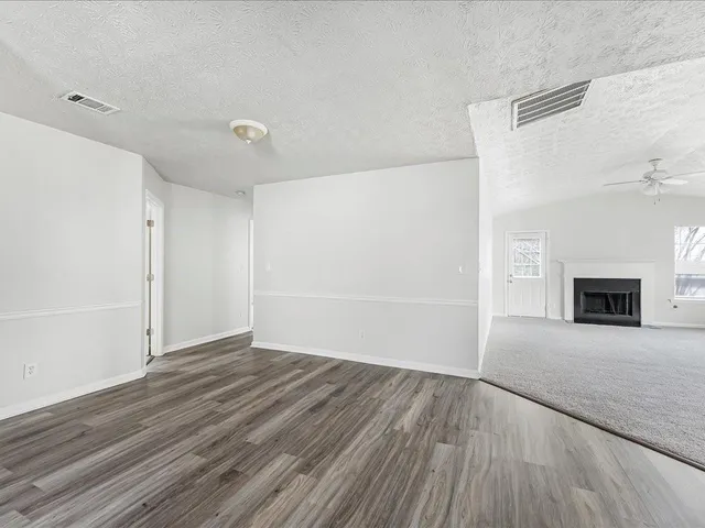 a view of an empty room with wooden floor and a fireplace