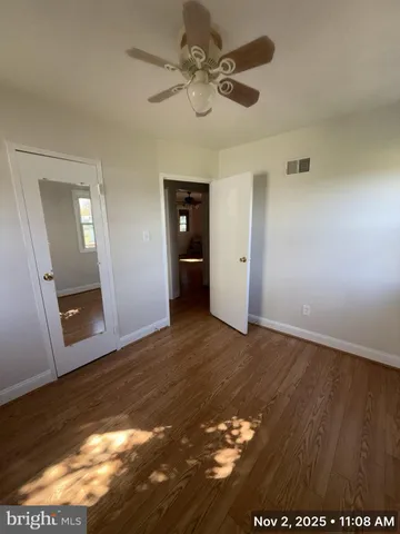 an empty room with wooden floor and fan