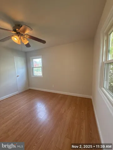 an empty room with wooden floor fan and windows