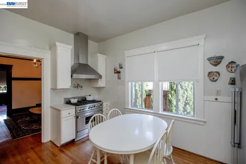 a kitchen with stainless steel appliances granite countertop a stove a refrigerator a sink a dining table and chairs