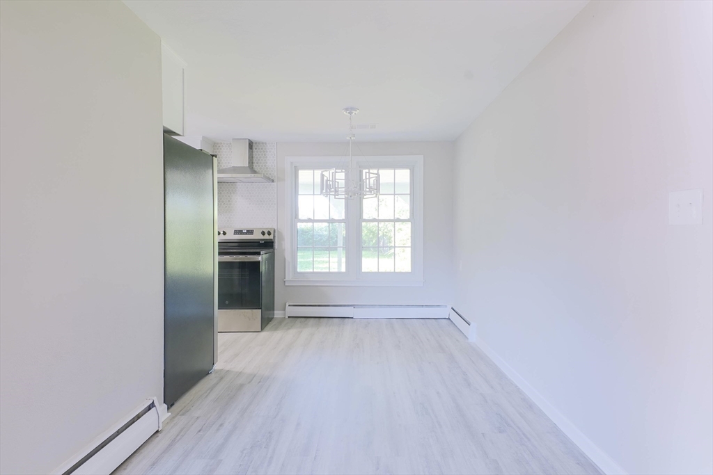 102 McCarthy Avenue Chicopee, MA 01020 - Photo 5 of 18 an empty room with wooden floor kitchen view and a window