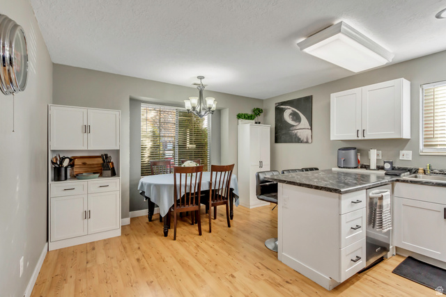 933 South Freedom Boulevard, Unit 7 Provo, UT 84601 - Photo 9 of 23 Kitchen featuring white cabinets, a chandelier, light wood finished floors, table nook area, and a textured ceiling