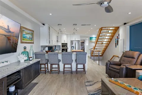 a living room with furniture kitchen view and a wooden floor