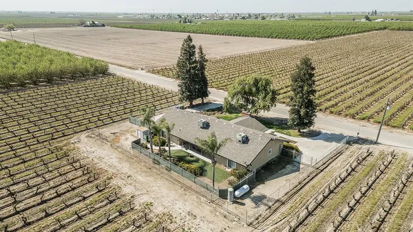 an aerial view of a house with yard and seating space