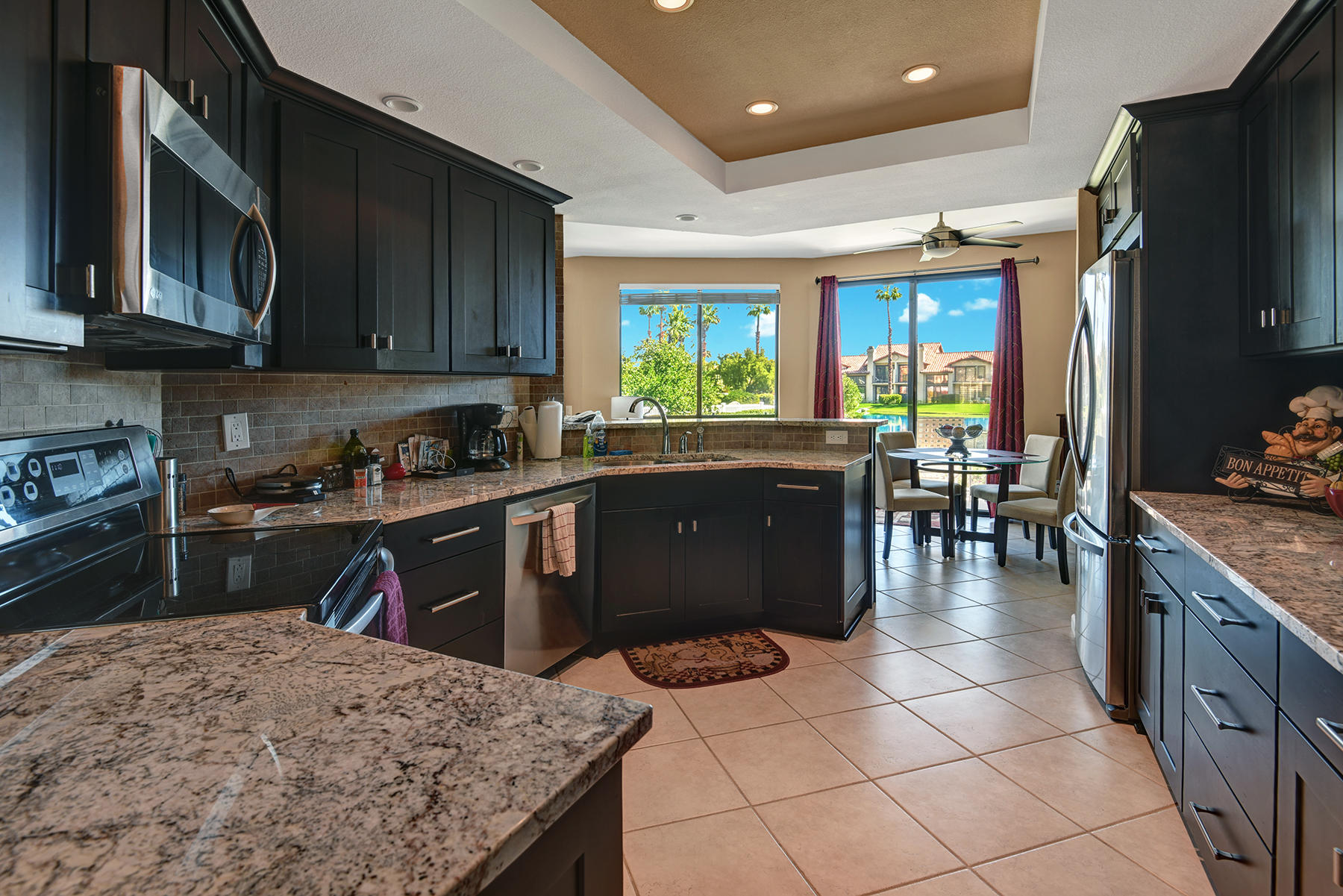 55108 Firestone La Quinta, CA 92253 - Photo 2 of 26 a kitchen with stainless steel appliances granite countertop a stove top oven a sink dishwasher a dining table and chairs with wooden floor