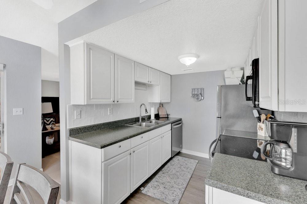 1024 North Plantation Drive, Unit B9 Kissimmee, FL 34741 - Photo 7 of 28 a kitchen with stainless steel appliances granite countertop a sink stove and refrigerator