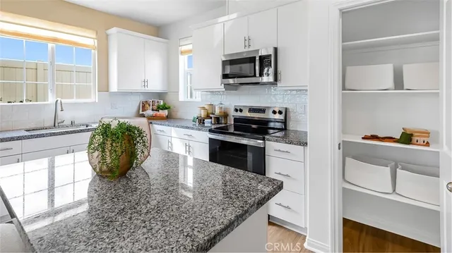 a kitchen with stainless steel appliances granite countertop a sink a stove top oven a counter space and cabinets
