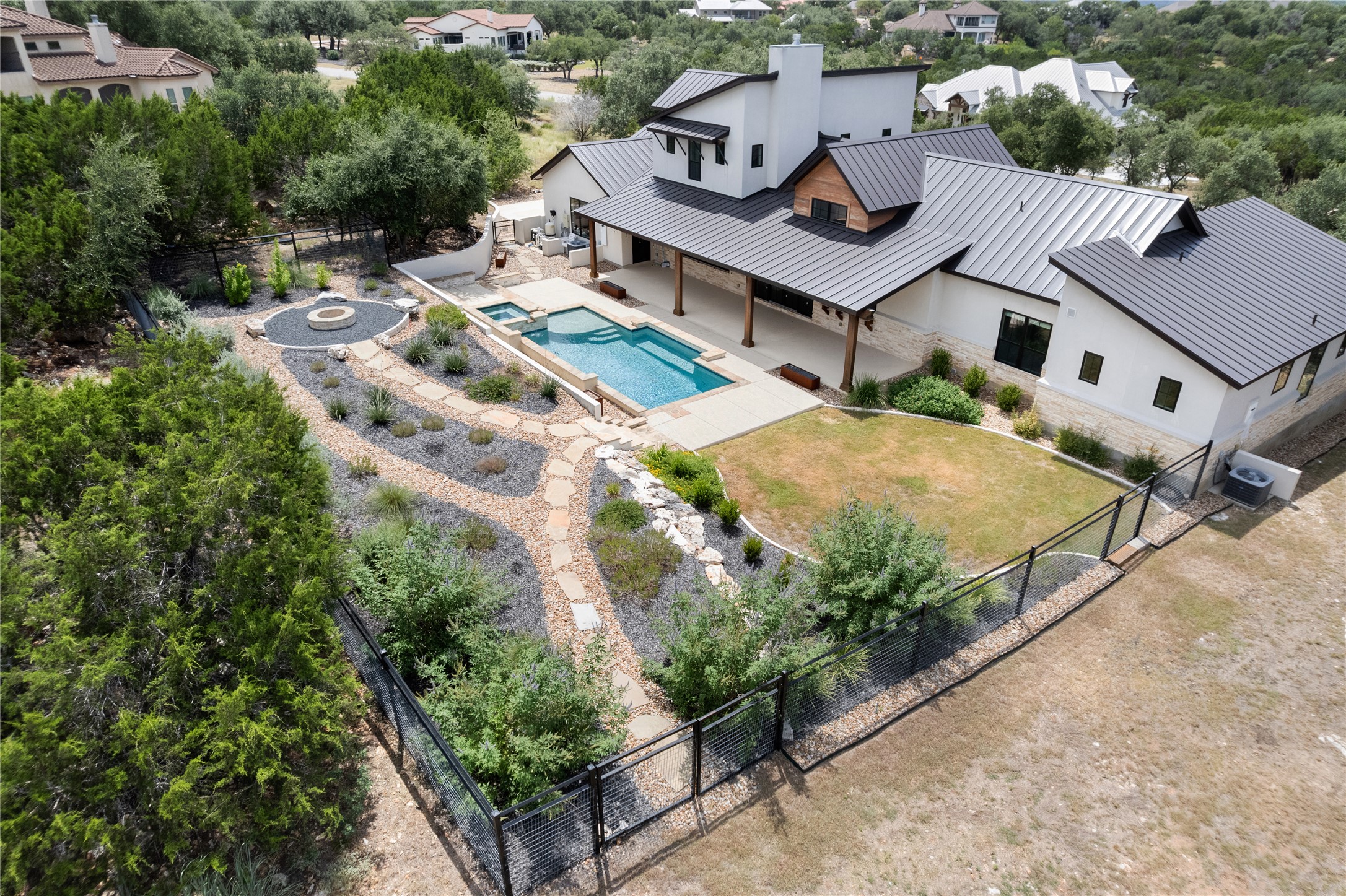 27619 Sunset Loop Garden Ridge, TX 78266 - Photo 36 of 39 A modern multi-level residence features a metal roof, swimming pool, and landscaped backyard paths.