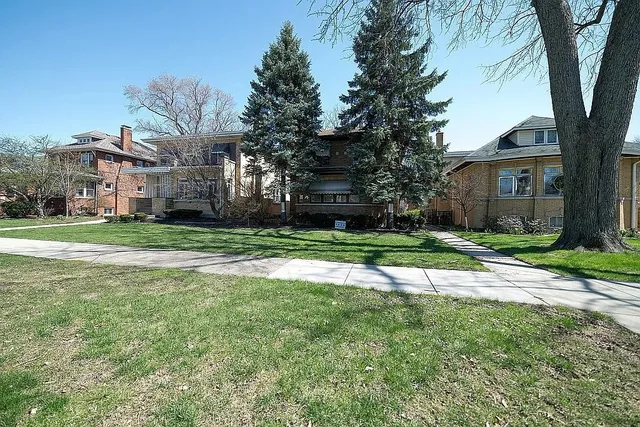 a view of a house with a big yard and large trees