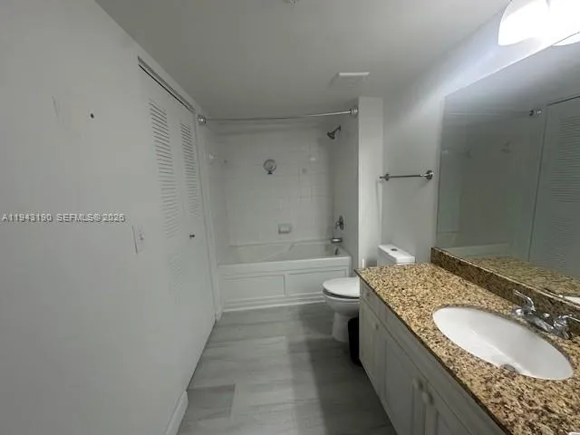 a bathroom with a granite countertop tub sink and mirror
