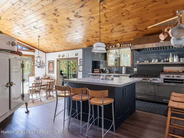 a kitchen with stainless steel appliances granite countertop a stove a sink dishwasher and chairs with wooden floor