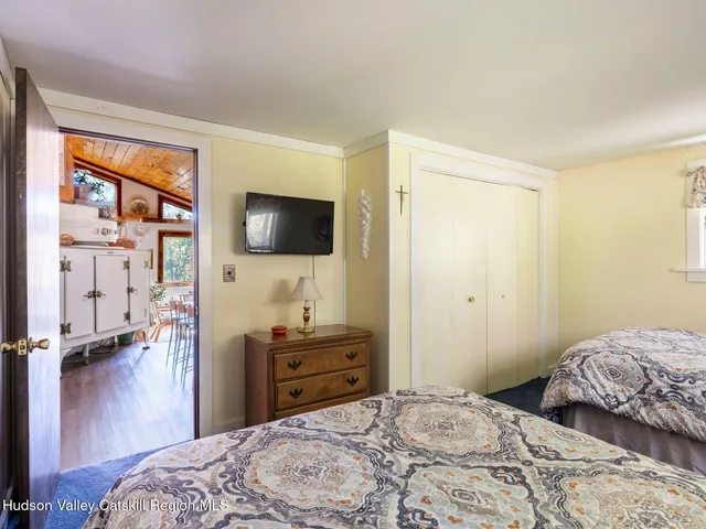 a bedroom with a bed and a flat tv screen on dresser