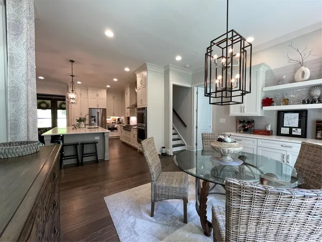 a kitchen with stainless steel appliances kitchen island granite countertop a refrigerator a stove and a dining table with wooden floor