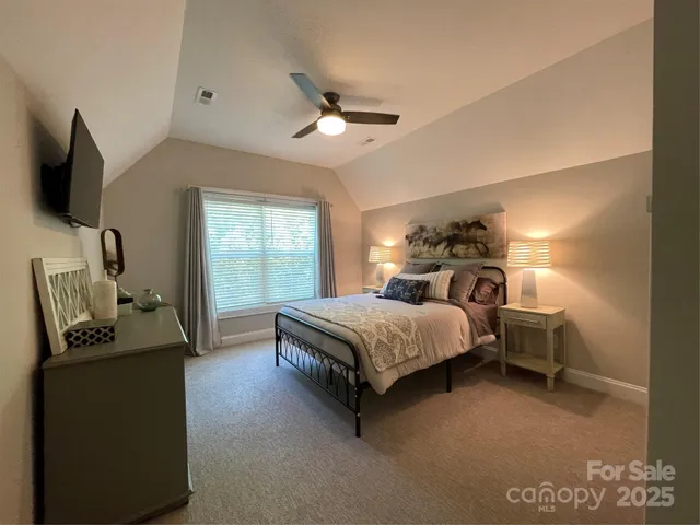 a bedroom with a bed and a flat tv screen on dresser