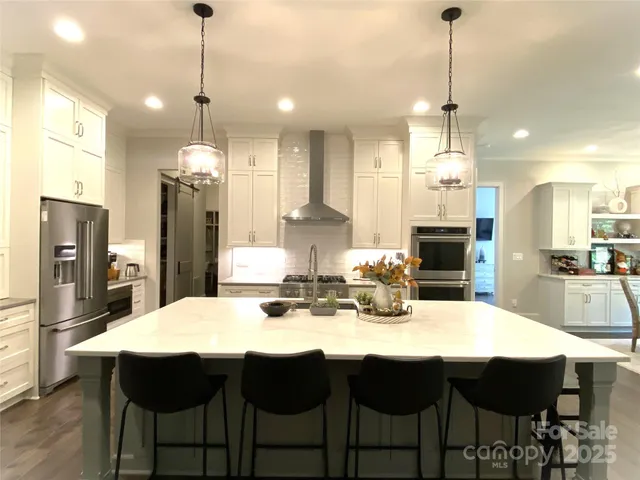 a kitchen with stainless steel appliances a dining table chairs and stove