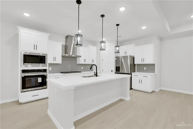 a kitchen with stainless steel appliances kitchen island granite countertop a sink a stove and a refrigerator