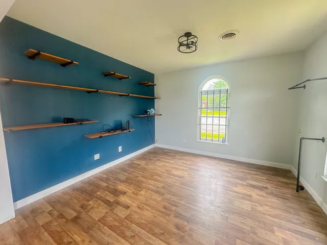 a view of an empty room with a window and wooden floor