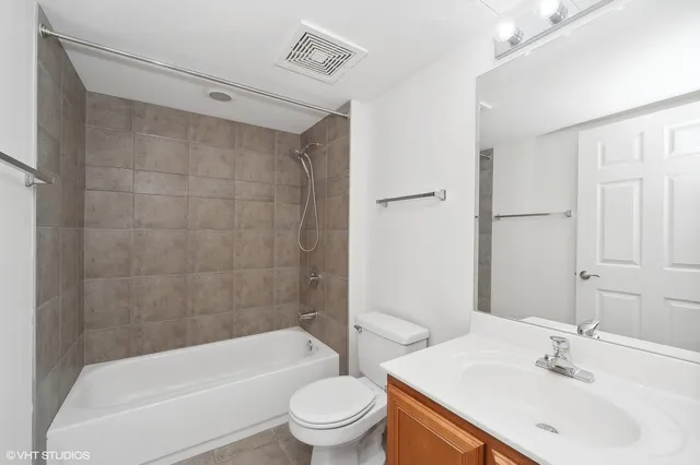a bathroom with a bathtub shower sink vanity mirror and toilet