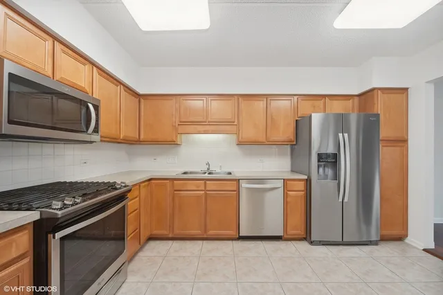 a kitchen with stainless steel appliances granite countertop a stove top oven a refrigerator and white cabinets