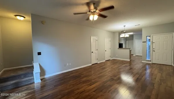 a view of a room with wooden floor chandelier and windows