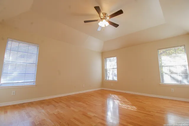 a view of an empty room with a window and wooden floor