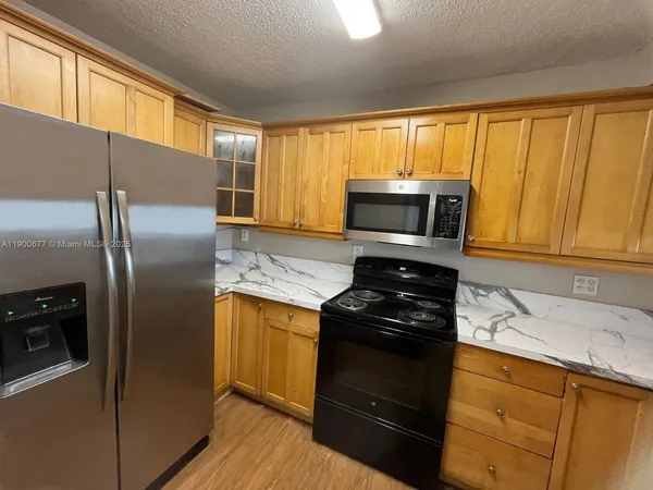 a kitchen with granite countertop a refrigerator stove and microwave
