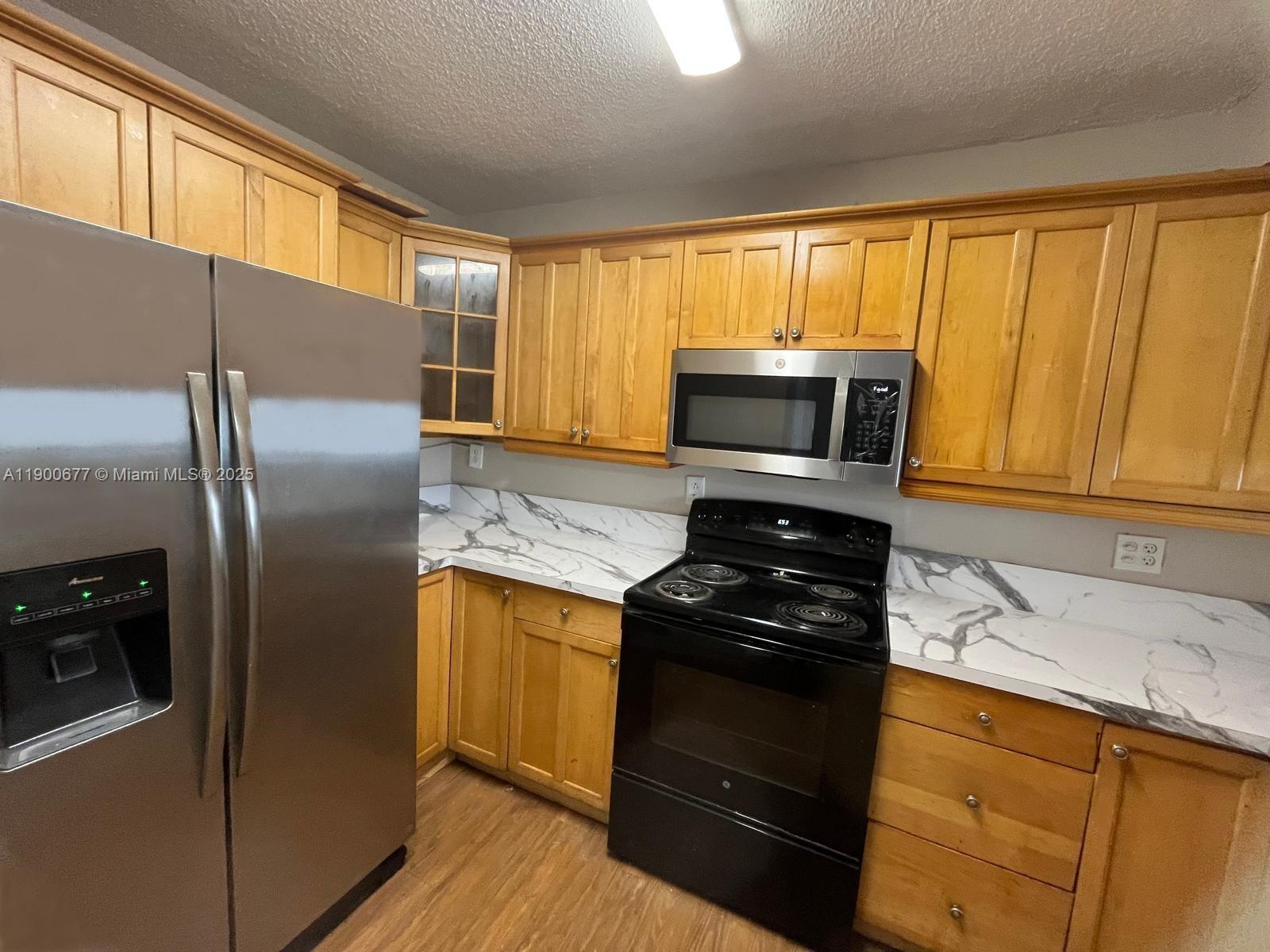 3400 Foxcroft Road, Unit 115 Miramar, FL 33025 - Photo 4 of 16 a kitchen with granite countertop a refrigerator stove and microwave
